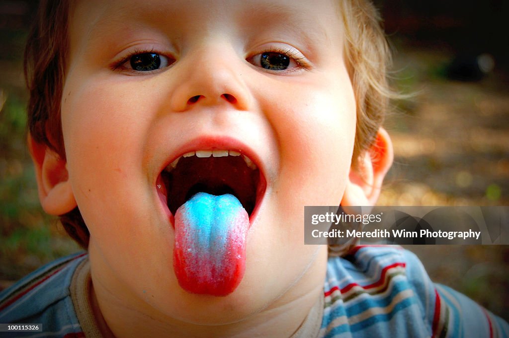 Young boy sticking out a blue tongue