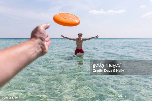 personal perspective of a man throwing a flying disc to a teenager - prospettiva del fotografo foto e immagini stock