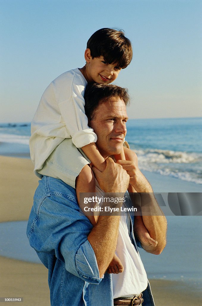 SON ON FATHER'S SHOULDERS AT BEACH