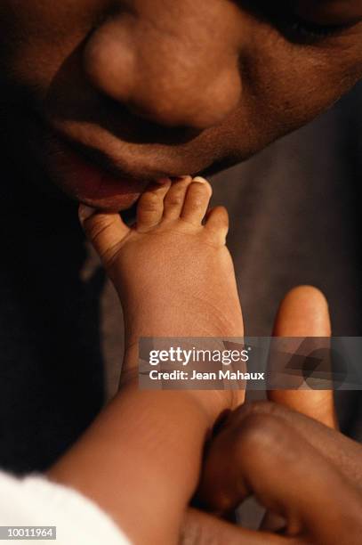 close-up of a black father kissing baby's foot - feet kiss stockfoto's en -beelden