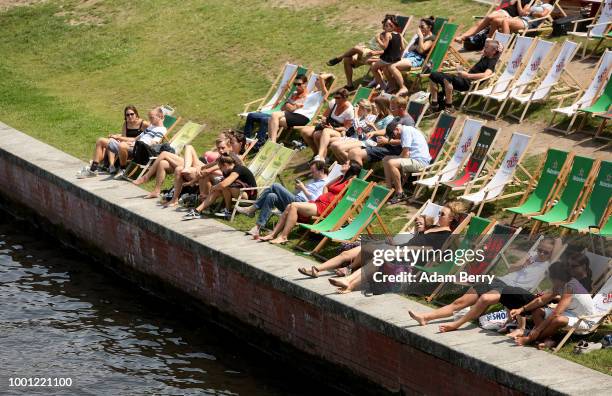 Visitors relax in the sun along the Spree river on July 18, 2018 in Berlin, Germany. Temperatures are expected to stay dry and hot in the city for...