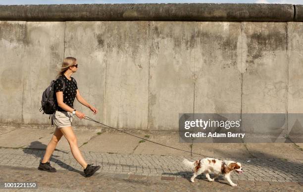 Woman walks her panting dog along the former Berlin Wall on July 18, 2018 in Berlin, Germany. Temperatures are expected to stay dry and hot in the...