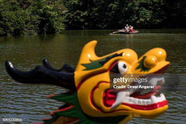 People paddle rowboats as a dragon boat sits in The Lake at Central Park before a traditional dragon boat awakening ceremony, July 18, 2018 in New...