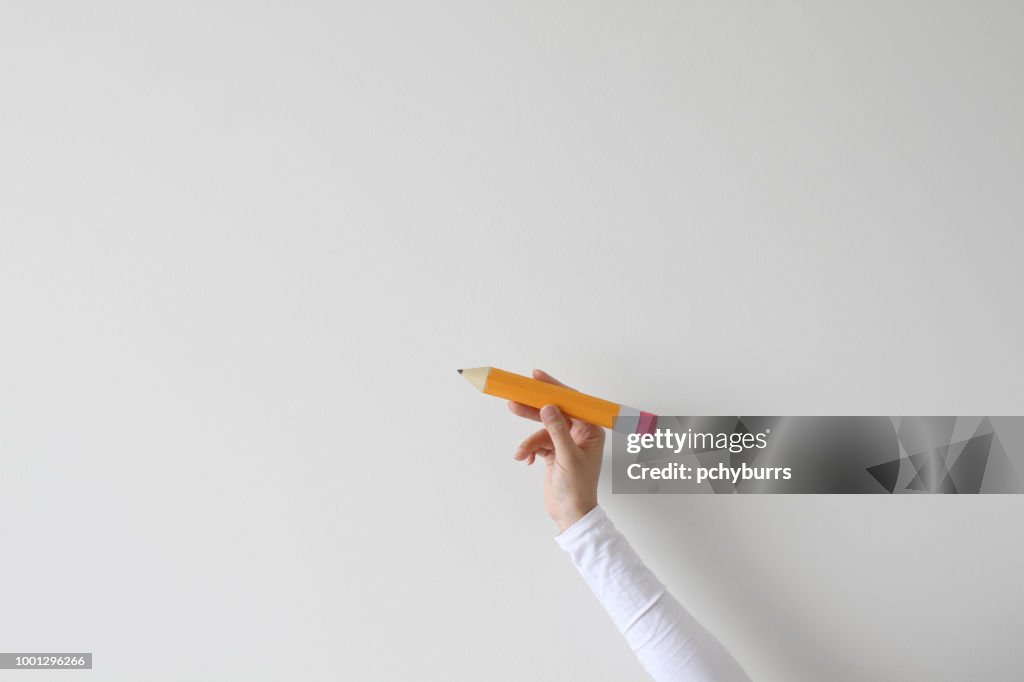 Woman's hand holding an oversized pencil
