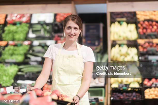 portrait of a smiling sales assistant standing in the fruit and vegetable section - produce aisle photos et images de collection