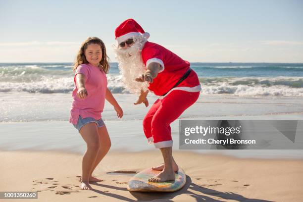 young girl showing santa claus how to surf on a surfboard - christmas in queensland stock pictures, royalty-free photos & images