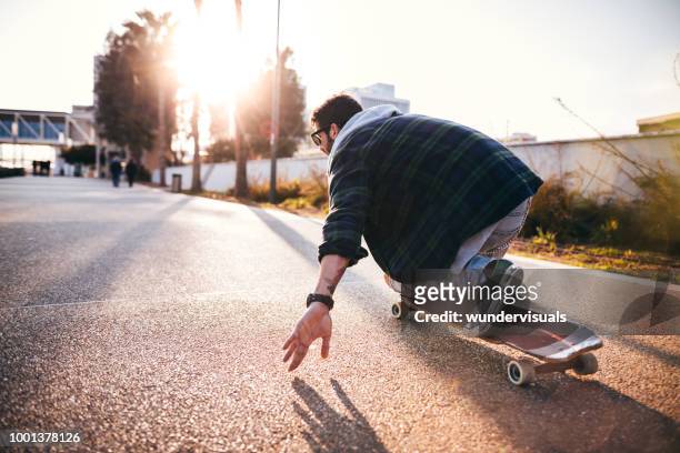 active hipster man skateboarding and having fun in the city - longboard surfing stock pictures, royalty-free photos & images