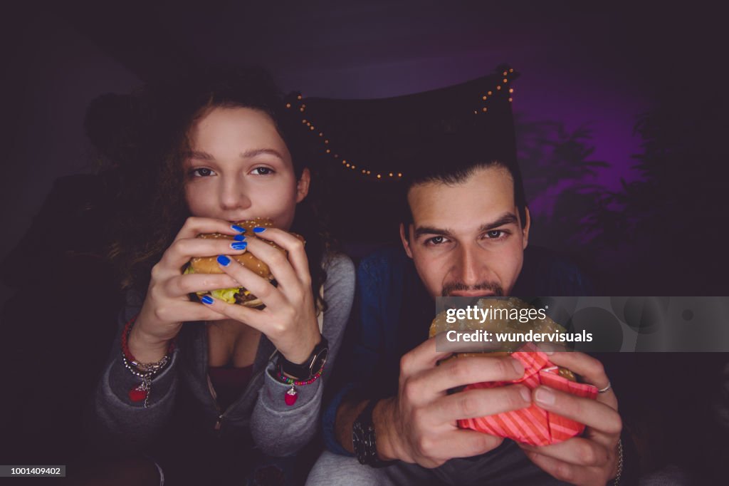Portrait of young man and woman eating hamburgers