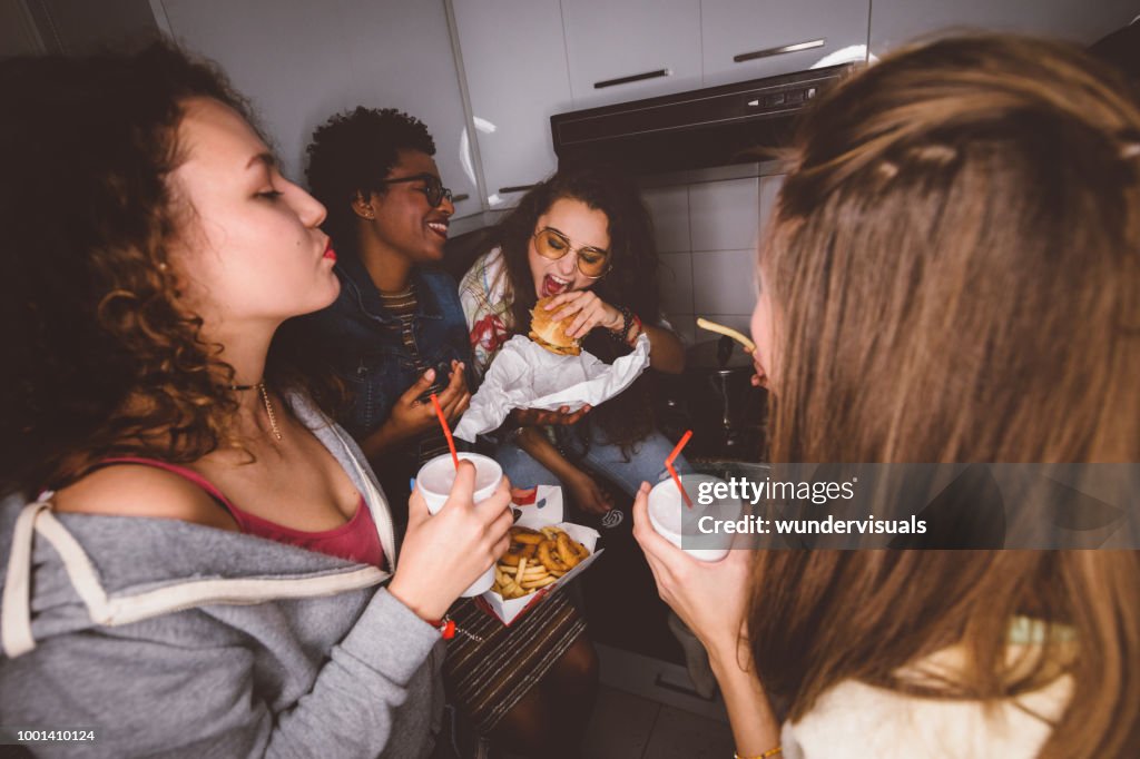 Young girls having fun eating fast food at house party