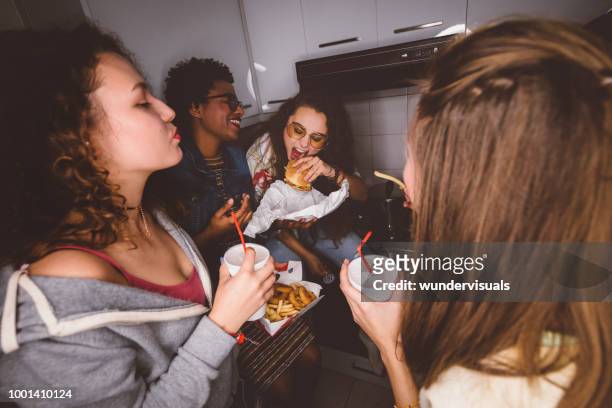 young girls having fun eating fast food at house party - college dorm party stock pictures, royalty-free photos & images