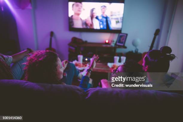 multi-ethnic teenage friends watching tv together at hangout house - watching stock pictures, royalty-free photos & images