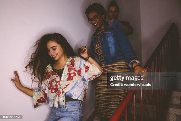 glücklich multiethnischen schelmischen jugendliche, die treppe hinunter laufen - college party stock-fotos und bilder