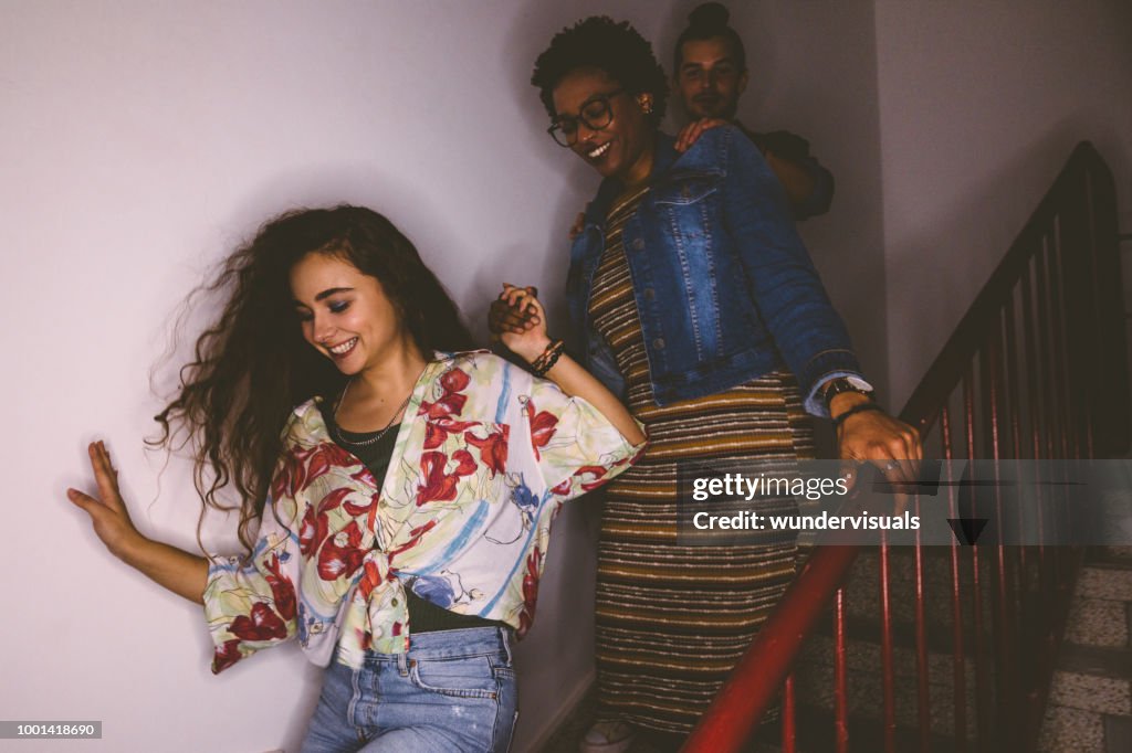 Happy multi-ethnic mischievous teenagers running down staircase