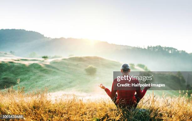 senior man meditating outdoors in nature in the foggy morning at sunrise. copy space. - runner sunrise stock pictures, royalty-free photos & images