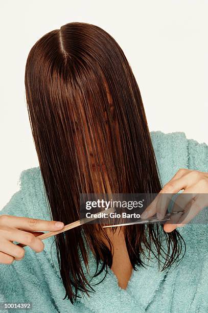 woman in robe cutting own hair - hair parting stockfoto's en -beelden