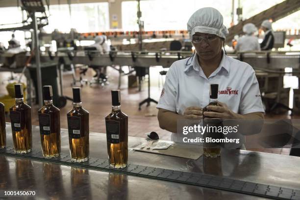 An employee applies labels to bottles of rum at the Ron Santa Teresa SACA distillery in El Consejo, Aragua state, Venezuela, on Tuesday, July 17,...