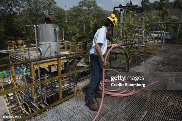 An employee arranges a hose in the distilling area at the Ron Santa Teresa SACA distillery in El Consejo, Aragua state, Venezuela, on Tuesday, July...