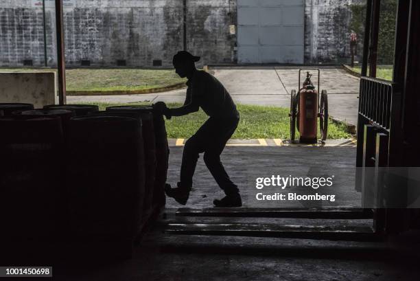 An employee moves oak barrels filled with rum at the Ron Santa Teresa SACA distillery in El Consejo, Aragua state, Venezuela, on Tuesday, July 17,...