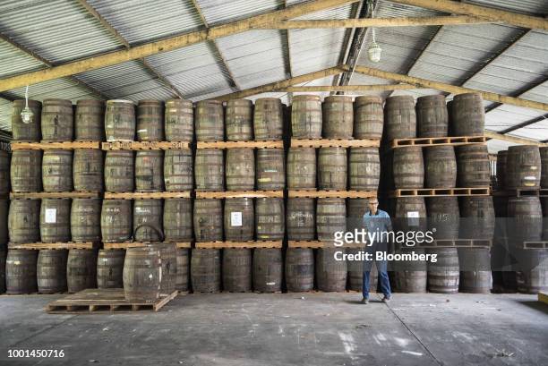 An employee walks past oak barrels filled with rum at the Ron Santa Teresa SACA distillery in El Consejo, Aragua state, Venezuela, on Tuesday, July...