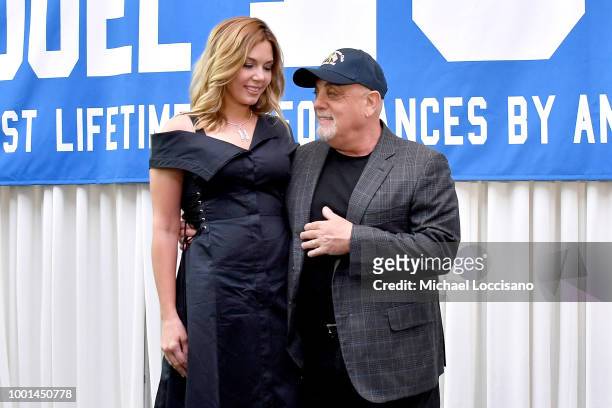 Billy Joel and wife Alexis Roderick pose in front of the banner during a press conference honoring Joel's 100th Lifetime Performance at Madison...