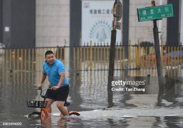 Man rides a bicycle on a flooded street caused by heavy rainstorms in Harbin city, northeast China's Heilongjiang province, 19 July 2018. Rainstorms...