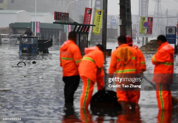 People drive a tractor on a flooded street caused by heavy rainstorms in Harbin city, northeast China's Heilongjiang province, 19 July 2018....