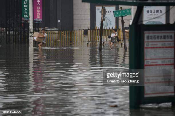 Pedestrians walk on a flooded street caused by heavy rainstorms in Harbin city, northeast China's Heilongjiang province, 19 July 2018. Rainstorms...