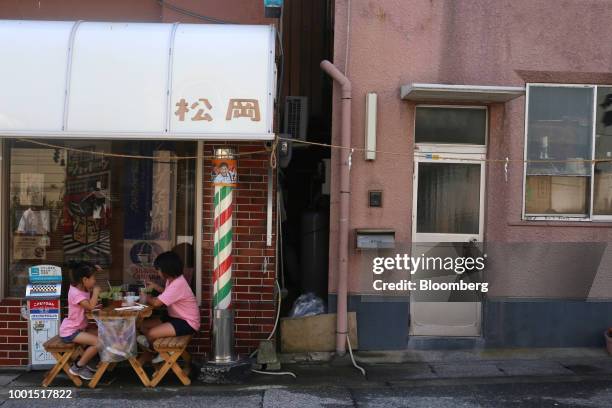 Girls sit in front of a barber shop in the Misakimachi area of Miura, Japan, on Saturday, July 14, 2018. Japan is scheduled to release consumer price...