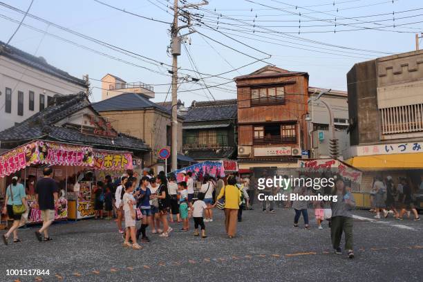 People walk past food stalls during the Kainan Shrine summer festival in the Misakimachi area of Miura, Japan, on Saturday, July 14, 2018. Japan is...