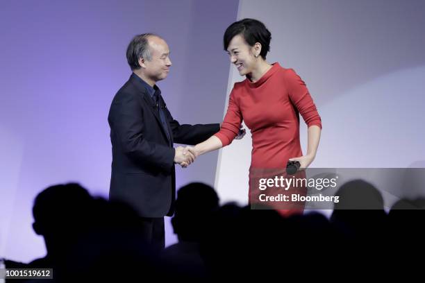 Masayoshi Son, chairman and chief executive officer of SoftBank Group Corp., left, shakes hands with Jean Liu, president of Didi Chuxing, at the...