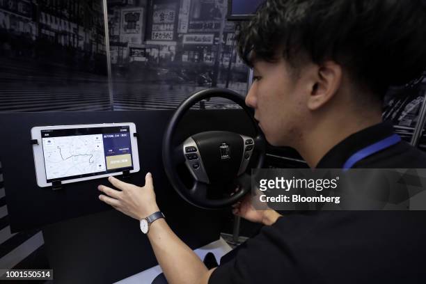 An attendant demonstrates the Didi Chuxing taxi-hailing application on a tablet device for a photograph at the SoftBank World 2018 event in Tokyo,...