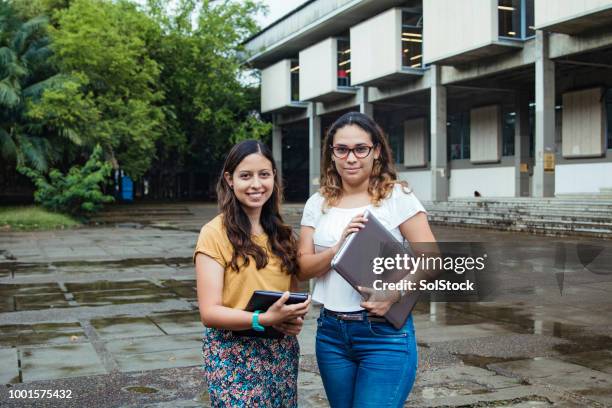 two female hispanic students proudly standing outside their university in cali colombia - cali morales stock pictures, royalty-free photos & images