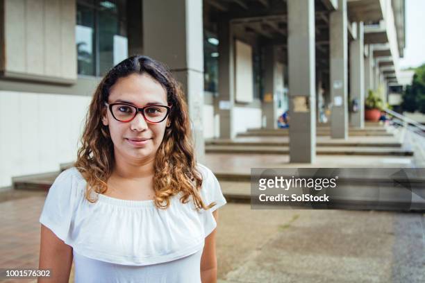 independent colombian female looking towards the camera, urban backdrop - cali morales stock pictures, royalty-free photos & images