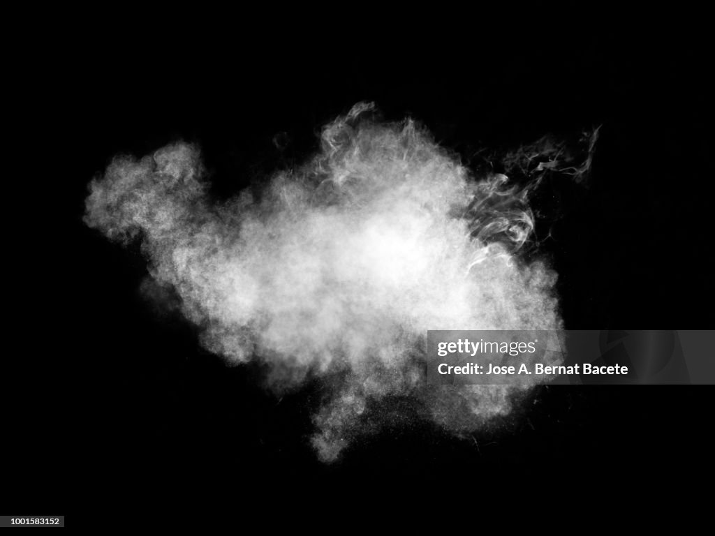 Full frame of forms and textures of an explosion of powder and smoke of color white and gray on a black background.
