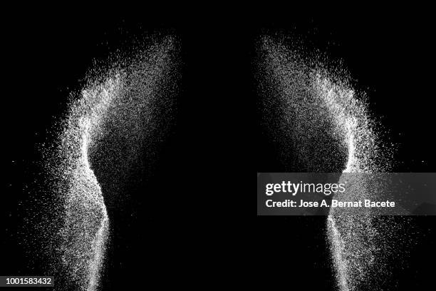 explosion by an impact of a cloud of particles of powder of color white on a black background. - blowing dust stock pictures, royalty-free photos & images