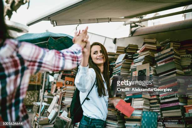 zwei freundinnen, die einander auf einen gruß buchmesse - book fair stock-fotos und bilder