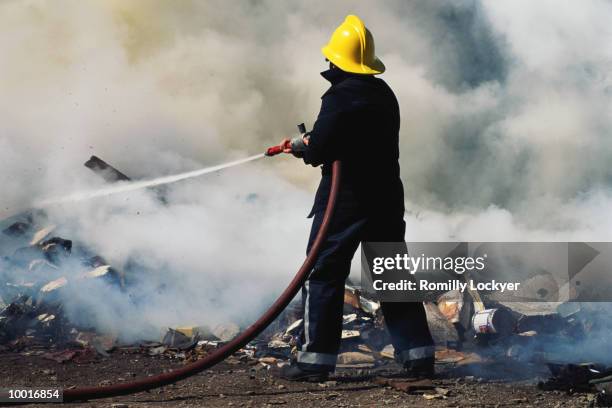 fireman hosing fire in united kingdom - firefighter uk stock pictures, royalty-free photos & images