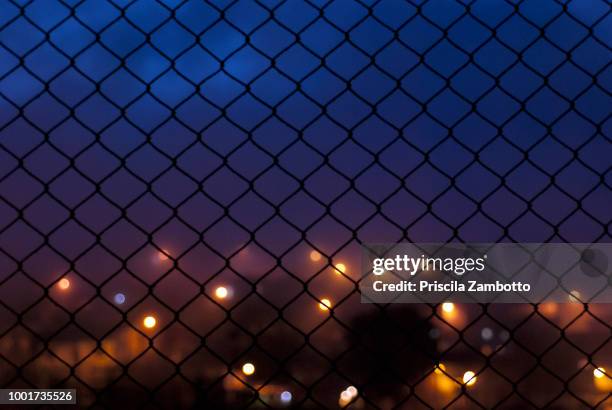 wire fence and defocused lights - wire mesh fence stock pictures, royalty-free photos & images