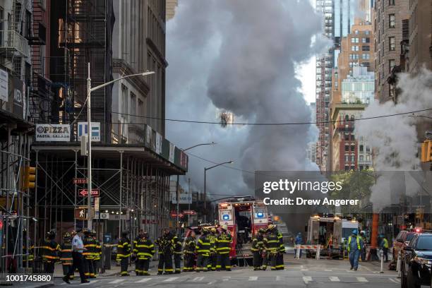 Firefighters work near the scene of a steam pipe explosion on Fifth Avenue near the Flatiron District, July 19, 2018 in New York City. Buildings were...