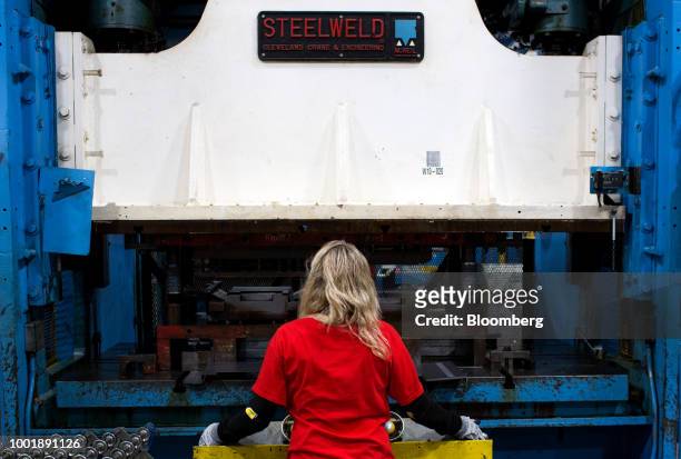 Worker places metal sheets into a stamping machine at a Stanley Black & Decker Inc. Craftsman Tools manufacturing facility in Sedalia, Missouri,...