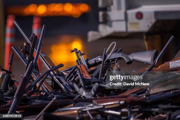 Molten slag is seen behind a pile of approximately 3,500 confiscated guns about to be destroyed at the Gerdau Steel Mill understand supervision of...