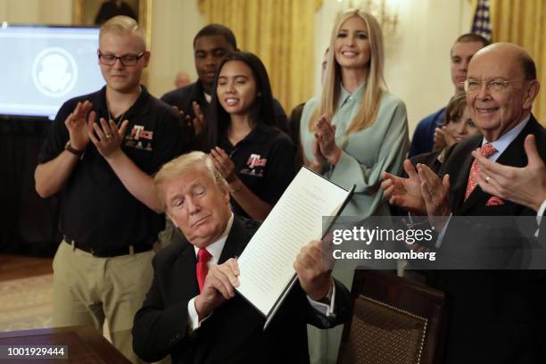 President Donald Trump holds up a signed executive order on workforce development during a 'Pledge to America's Workers' event at the White House in...