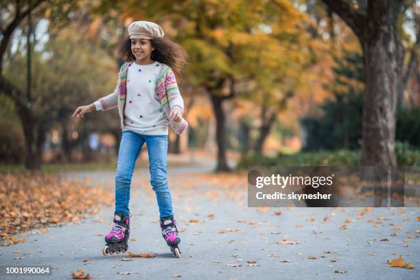 gelukkig african american girl plezier op haar roller klapschaatsen in het park. - skaten stockfoto's en -beelden