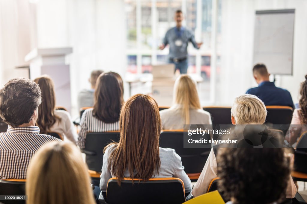 Rear view of business people attending a seminar in board room.