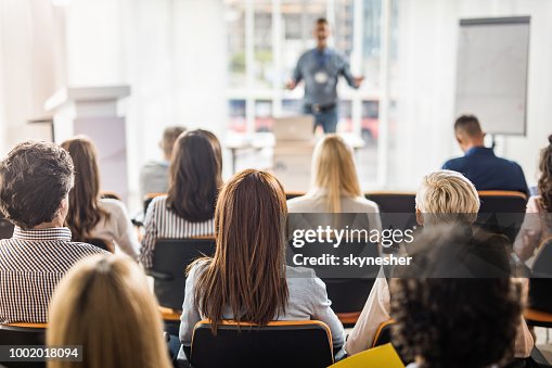 Rear view of business people attending a seminar in board room. Rear view of business people attending a seminar in board room.