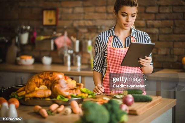 mujer joven con tableta digital en día acción de gracias en la cocina. - christmas turkey fotografías e imágenes de stock