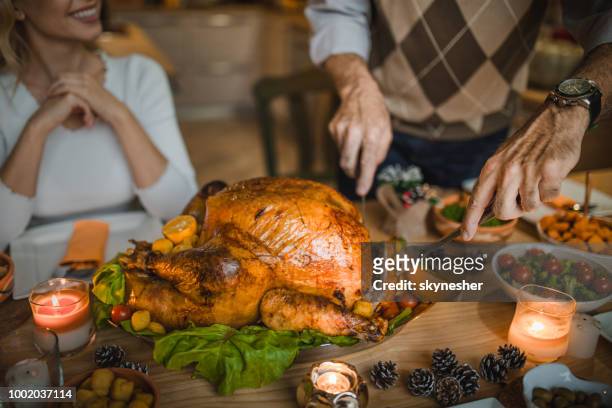 unrecognizable person carving roasted turkey during thanksgiving dinner at dining table. - christmas feast stock pictures, royalty-free photos & images