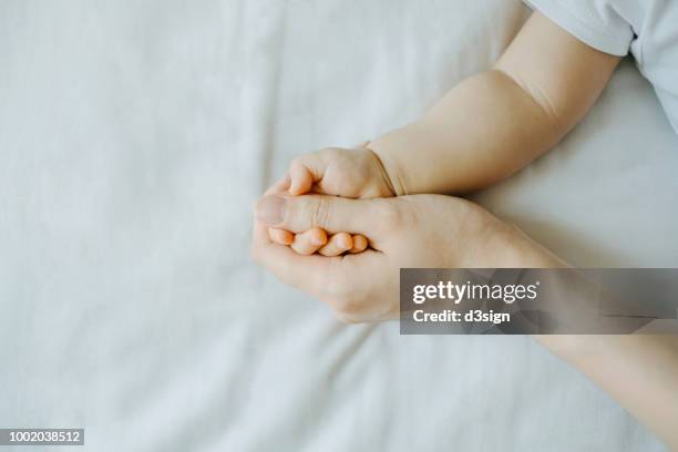 close up of mother holding baby's hand against white background - mom holding baby fotografías e imágenes de stock