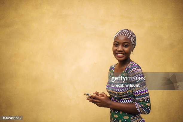 schönes porträt eines afrikanischen mädchens auf ihrem mobiltelefon frauenpower - afrikanische kultur stock-fotos und bilder