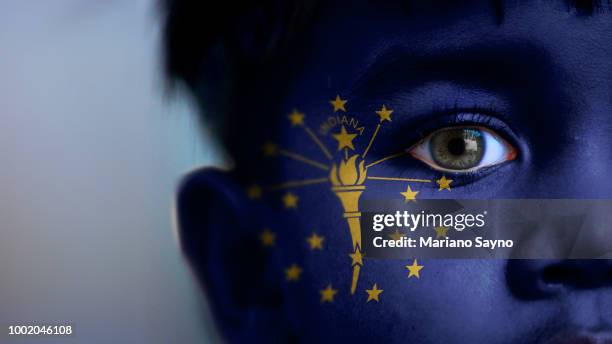 boy's face, looking at camera, cropped view with digitally placed indiana state flag on his face. - indiana flag stock pictures, royalty-free photos & images